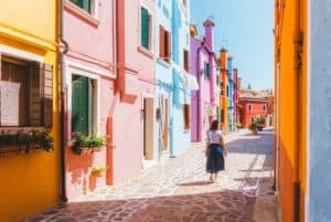 a woman walks the colorful streets in Burano Venice