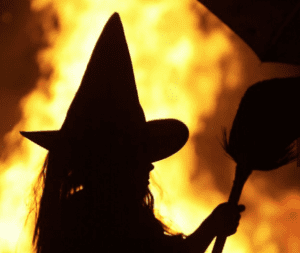A young girl is illuminated by a bonfire dressed as a which in Halloween Traditions