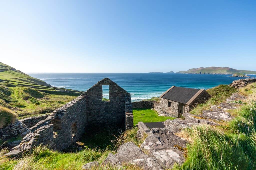 A sunny Irish sky shines on the remains of an old home and the sea