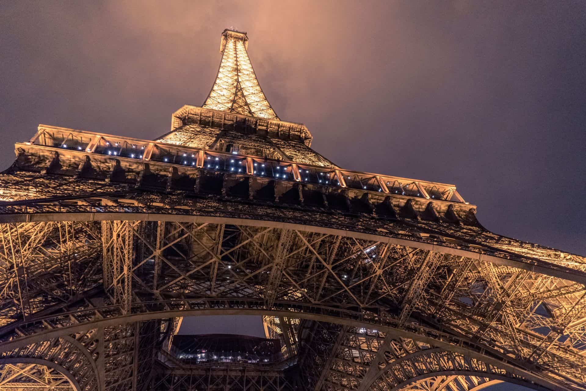The view of the Eiffel Tower from ground level at night