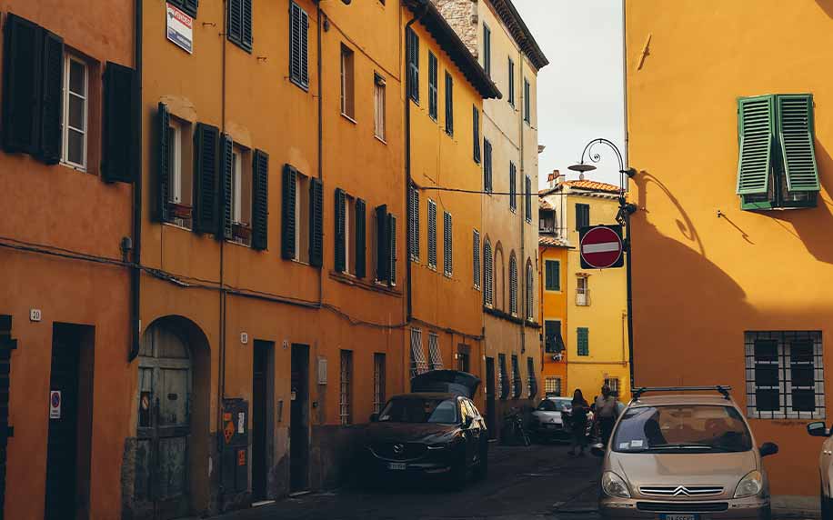 a street in lucca with bright yellow architecture and cobbled stone roads