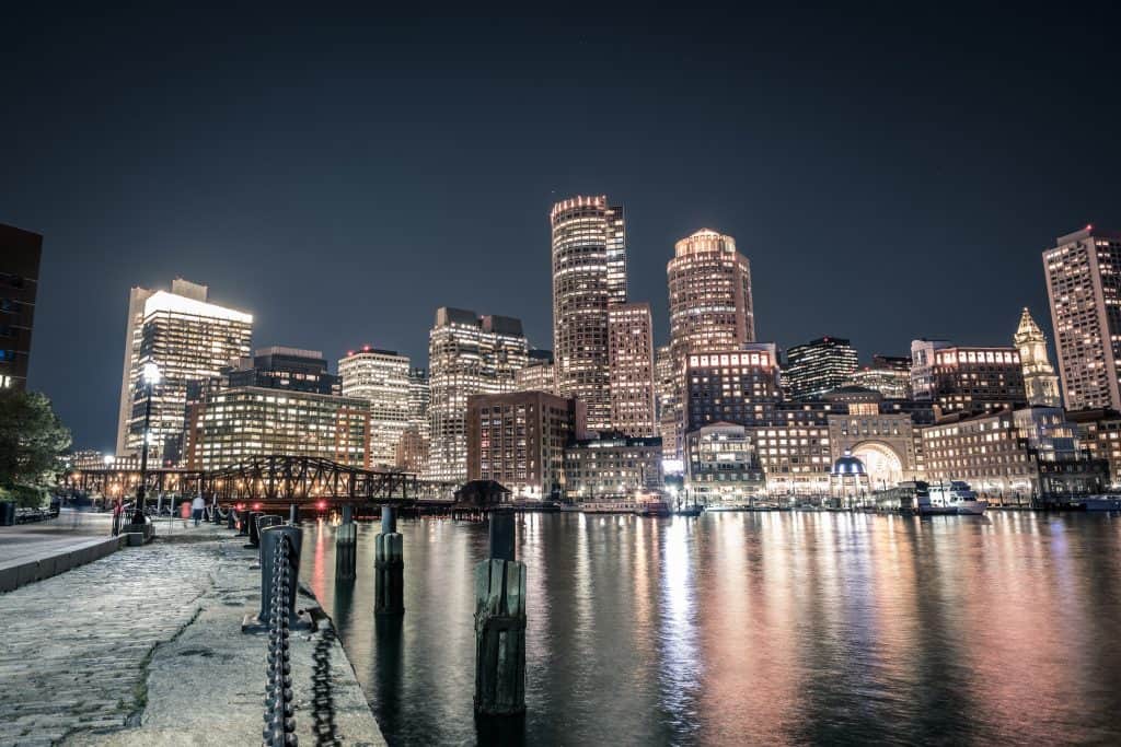 The city skyline lit at night reflection on the waters of Boston