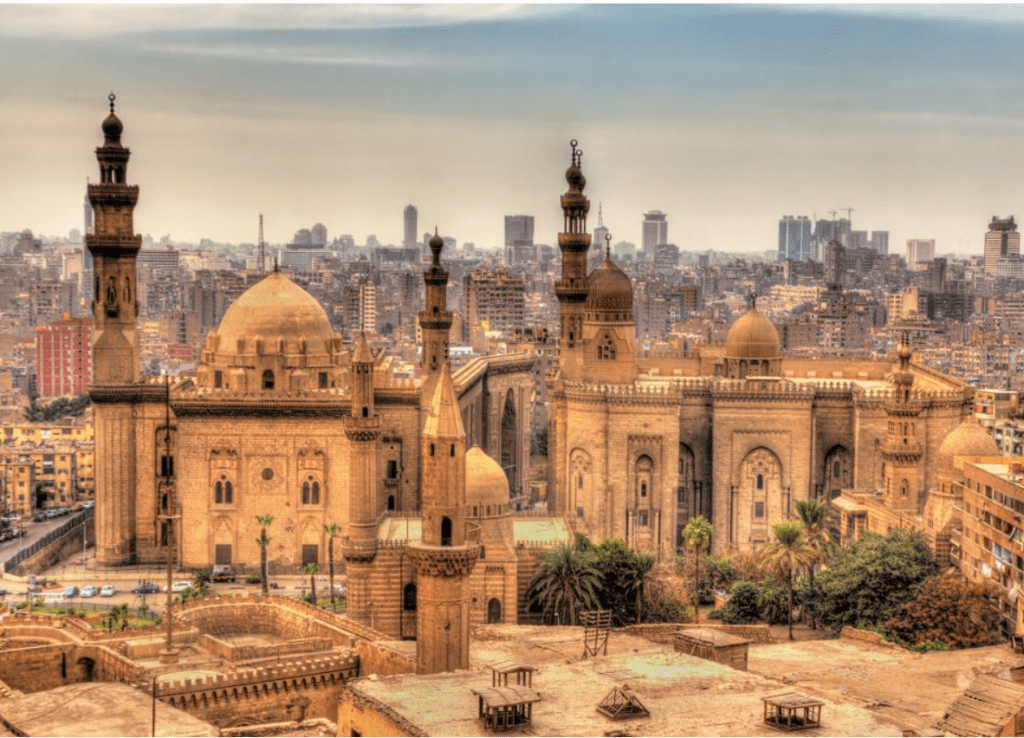 A mosque set in the center with the modern city of Cairo in the distance.