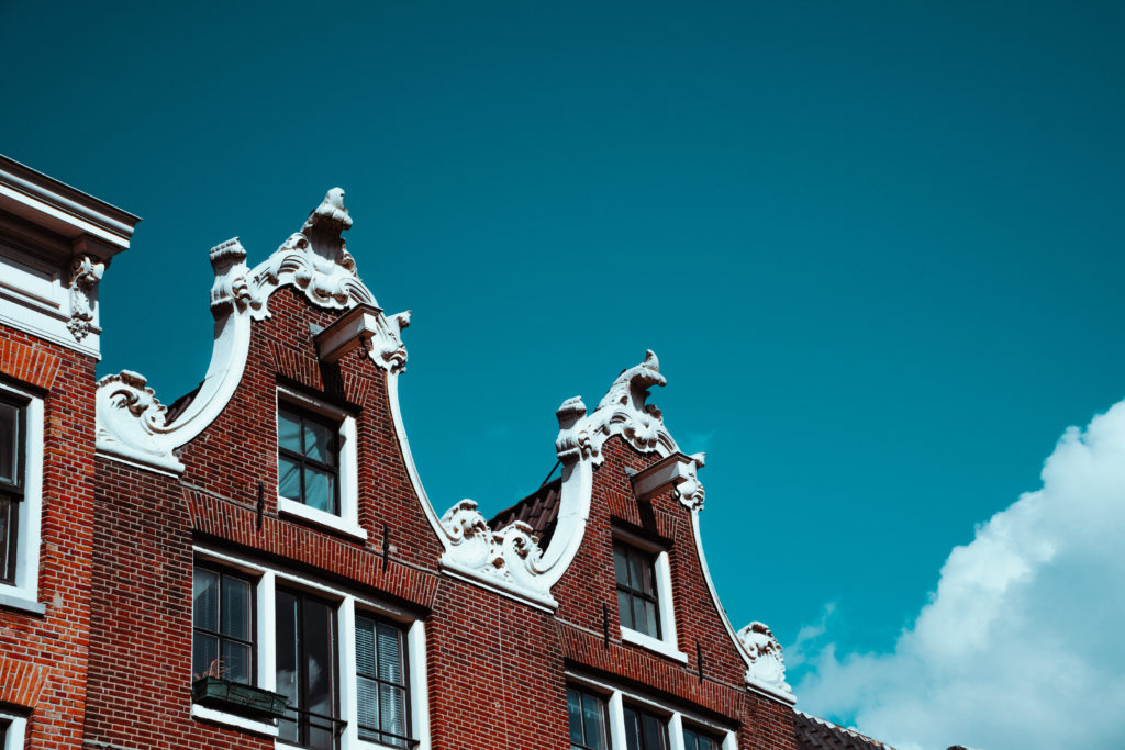 Close-up of the old building facade and roof decoration against blue sky in Amsterdam. Architectonic Details Northern Netherlands.
