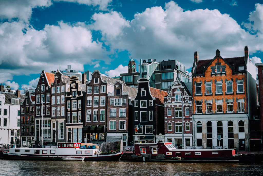 The wonderful architecture of Amsterdam. White fluffy clouds over Leaning Houses Amsterdam, Netherlands.