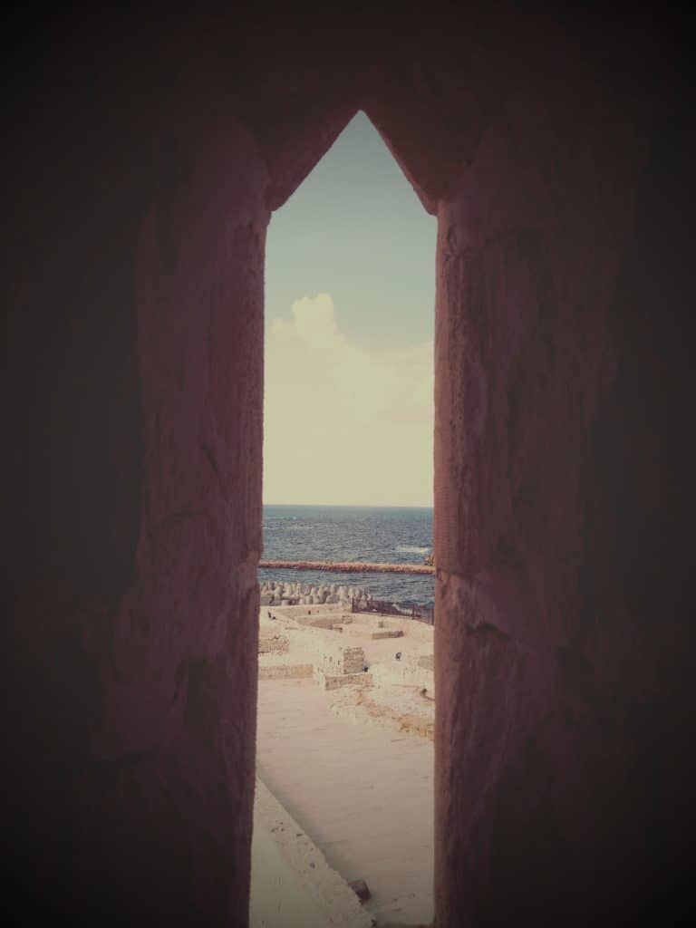 A window facing the courtyard and the Mediterranean in the background  
