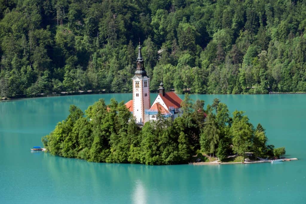 Lake Bled Unspalsh Featuring an island in the middle of a mesmerising crystal clear water coloured lake, called Lake Bled, Bled is one of the most known and visited places in Slovenia. Located in the lower hills of the Julian Alps, this place owns a magical wonderland landscape which is a must-visit if you go to Slovenia.