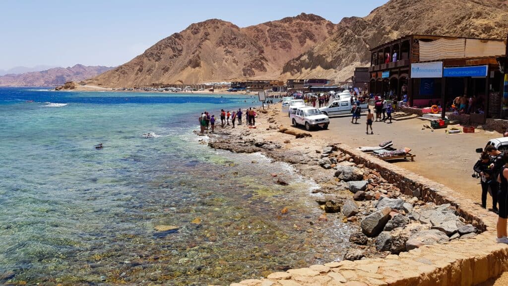 dahab 2 min Dahab, a town that used to be a Bedouin fishing village, is currently one of the most important tourist destinations in Egypt. The word “Dahab” is an Arabic word that is translated into “Gold”. And Dahab’s gold lies in its nature. From sea to land, visitors do a variety of activities and connect to the beauty and wonders of unique natural scenery.  It lies on the southeast coast of the Sinai Peninsula, approximately 80 km northeast of Sharm El-Sheikh. Tourists can book a bus from Sharm El-Sheikh airport and reach Dahab in less than 2 hours for less than $10.