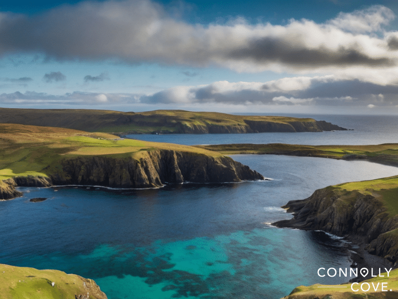 Shetland Islands
Aerial view of rugged coastal cliffs and green pastures on a remote archipelago, bordering a deep blue bay under a partly cloudy sky. “Connolly Cove” watermark in the lower right corner.