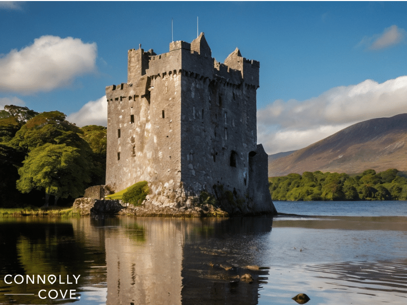 Ross Castle sits on the edge of a lake, surrounded by trees and hills under a partly cloudy blue sky. The words "CONNOLLY COVE" appear in the bottom left corner.