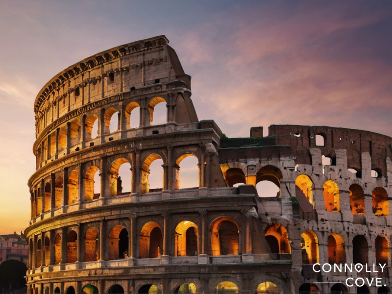 Rise and Fall of the Roman Republic
The Roman Colosseum is illuminated at sunset, showcasing its arches and ancient stone structure—a lasting symbol of the Roman Republic—against a colorful sky. Connolly Cove is written in the bottom right corner.