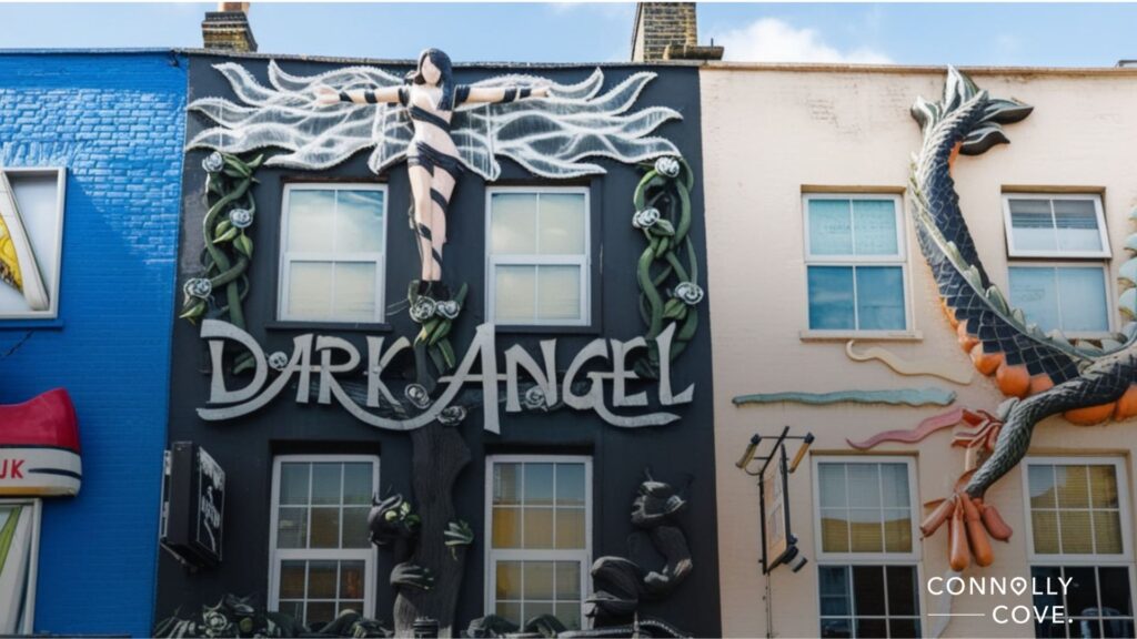 A building facade with bold 3D art, featuring a winged figure on a cross above the words Dark Angel and a large dragon sculpture next door—striking highlights amid the vibrant London nightlife on this colorful street.