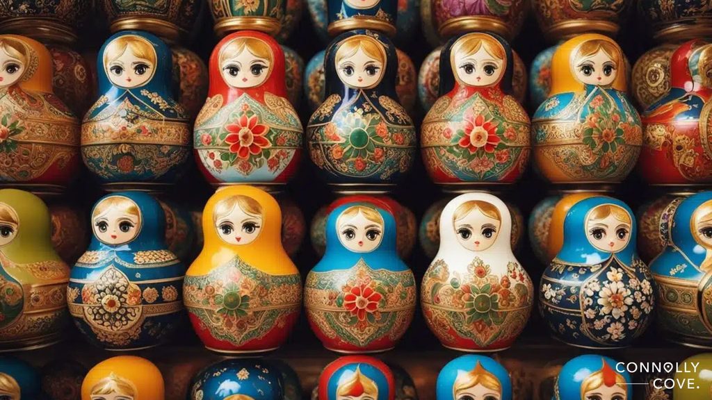 Rows of brightly coloured Russian nesting dolls, a stunning example of Traditional Russian Folk Art, with floral and ornate patterns, featuring wide-eyed faces. The bottom right corner displays the text CONNOLLY COVE.