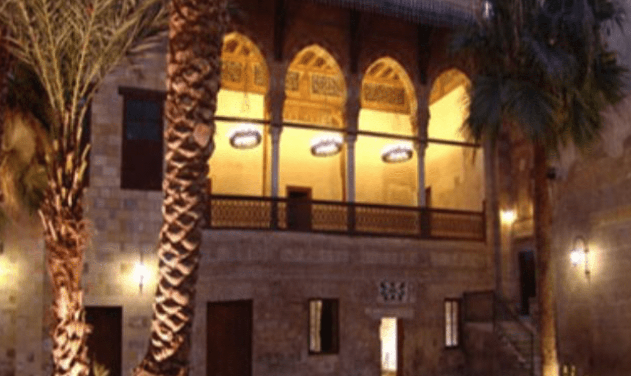 The Palace of Prince Taz in Cairo is lit at night and surrounded by palm trees.