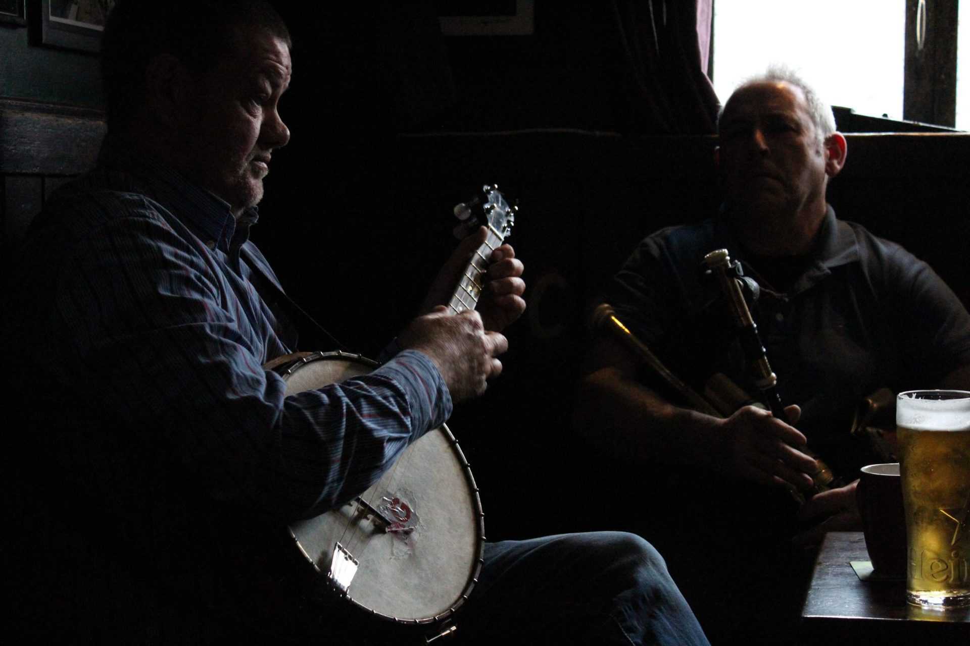 Two musicians sitting in a pub with instruments