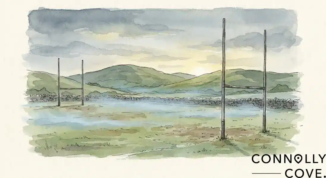 Watercolour painting of a rural Irish landscape featuring a Gaelic football pitch with H-shaped goalposts and distant hills, with the Connolly Cove logo in the corner representing the spirit of Irish athletics.