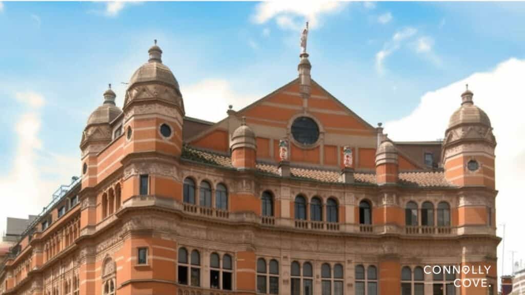 A historic, ornate building with orange and beige brickwork, arched windows, and decorative towers stands under a blue sky in Soho London. The name CONNOLLY COVE appears in the bottom right corner.