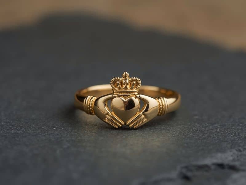 Close-up of a gold Claddagh ring showing the clasped hands, heart and crown symbols